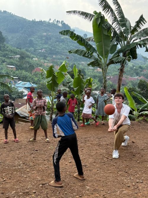 Children playing football with a visitor outside the orphanage